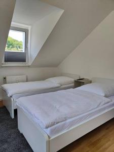2 bedden in een witte kamer met een raam bij SANO Apartments - DGL - Hagen Zentral - vollausgestattete Küche - Internet - Platz für bis zu 5 Personen in Hagen