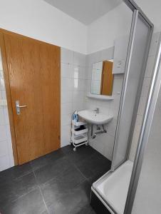 een badkamer met een wastafel en een houten deur bij SANO Apartments - DGL - Hagen Zentral - vollausgestattete Küche - Internet - Platz für bis zu 5 Personen in Hagen
