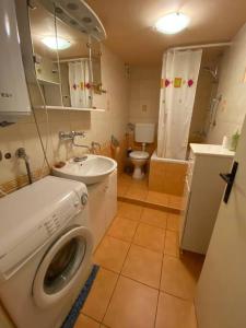 a bathroom with a washing machine and a sink at Cozy & quiet studio apartment with a garden in Split