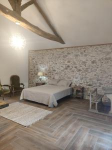 a bedroom with a bed and a stone wall at Le Domaine De Dolly in Villeneuve-sur-Lot