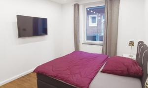 um quarto com uma cama e uma televisão na parede em Moderne Ferienwohnung direkt am Kanal / Neubau em Emden