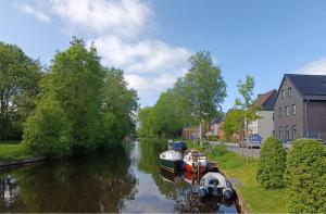 dois barcos estão ancorados num rio numa cidade em Moderne Ferienwohnung direkt am Kanal / Neubau em Emden