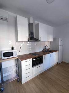 eine Küche mit weißen Schränken, einer Spüle und einer Mikrowelle in der Unterkunft Apartamento Delux1 in Valencia