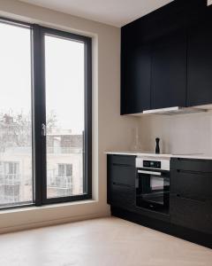 オスロにあるFully serviced luxury apartment at Sommerroのキッチン(黒いキャビネット付)、大きな窓