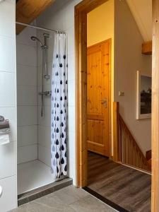 y baño con ducha a ras de suelo y cortina de ducha. en Unieke houten villa met SAUNA in Twente - 6p, en Den Ham