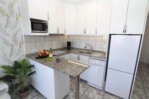 a kitchen with white cabinets and a granite counter top at Apartments ALOE TOP FLOOR in Playa del Ingles