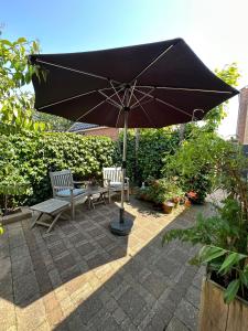 an umbrella and two chairs and a table and benches at ZeeBedStay in Noordwijk aan Zee