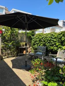 a black umbrella and two chairs and a bench at ZeeBedStay in Noordwijk aan Zee