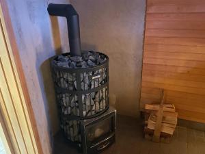 a wood stove with a trash can in a room at Napapiirin Eräkartano in Pello