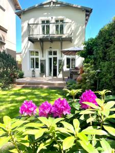 una casa con flores rosas delante de ella en Agapella Apartamenty- Sopot Cottage Ogród 400m od plaży 6 dorosłych i dzieci en Sopot