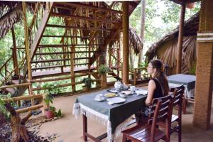 a woman sitting at a table in a room at Eco Village in Ella