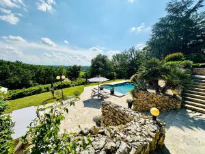 a backyard with a swimming pool and a stone wall at Suite Armagnac, relaxing gite near Nogaro in Nogaro