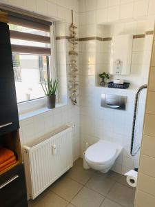 a white bathroom with a toilet and a window at Ferienwohnung Am Maarbach in Konz