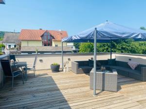 un patio con una sombrilla azul en una terraza en Ferienwohnung Am Maarbach, en Konz