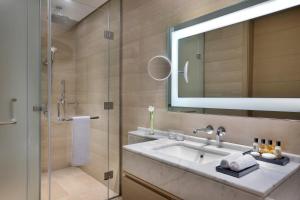 a bathroom with a sink and a shower with a mirror at Jeddah Marriott Hotel Madinah Road in Jeddah