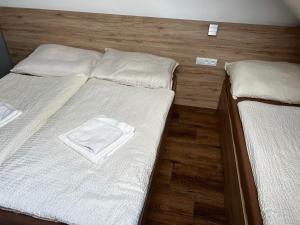 a bedroom with two beds with white sheets and wooden floors at Hotel U Kociana in Trojanovice