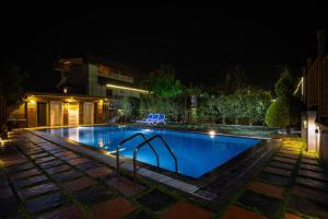 a swimming pool at night with chairs around it at Star Emirates Luxury Resort and Spa, Munnar in Anachal