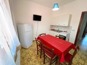 una cucina con tavolo rosso e frigorifero bianco di Soleado Apartments Caprioli-Palinuro a Palinuro