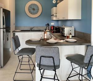 two pictures of a kitchen with a counter and chairs at Appart T3 4 étoiles 4/6 personnes Porto Vecchio in Porto-Vecchio
