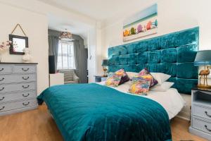 a bedroom with a blue headboard and a bed at Sea view Ar Lan y Mor LUXURY APARTMENT in Aberystwyth