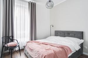 1 dormitorio con 1 cama, 1 silla y 1 ventana en Apartament Chwaliszewo, en Poznan