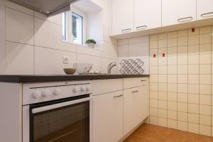 a white kitchen with a stove and a sink at Rustico Porta in Brissago