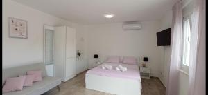 a white bedroom with a white bed and pink pillows at Apartman Punta Radman in Petrcane