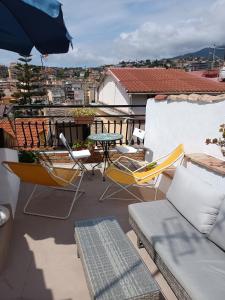 - Balcón con sillas, mesa y sombrilla en Attico romantico con terrazza Sanremo - Palm Street, 104, en San Remo