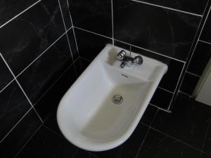 lavabo blanco en un baño de azulejos negros en Split Apartments 1-2 en Split