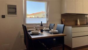 una mesa de comedor con una botella de vino y copas en Apartma Lima en Ankaran