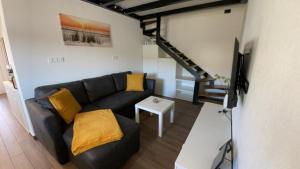 sala de estar con sofá negro y TV en Apartma Lima en Ankaran