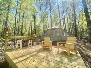 a tent and chairs on a deck in the woods at Sailor Springs Glamping in Bayfield