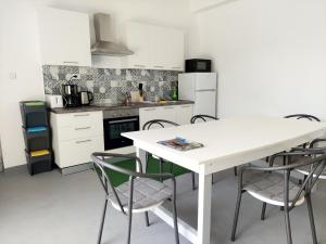 a white kitchen with a white table and chairs at Rooms Ive in Lozovac