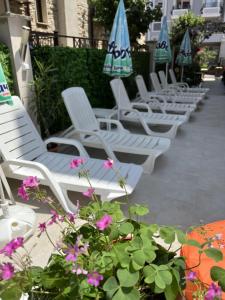 a row of white lounge chairs with umbrellas and flowers at Tabanov Beach Hotel in Sozopol