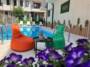 a pool with two chairs and a table and purple flowers at Tabanov Beach Hotel in Sozopol
