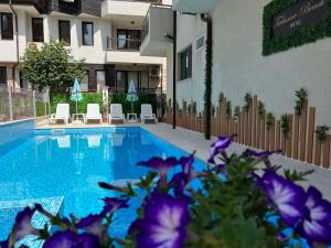 a swimming pool with purple flowers in front of a building at Tabanov Beach Hotel in Sozopol