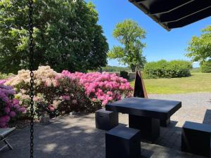 a swing in a garden with pink flowers at Skovlandshuset in Hadsten Stationsby