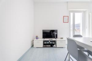 a white living room with a tv and a table at Windsurfer's Suite - Garda Lake View in Nago-Torbole +12 photos