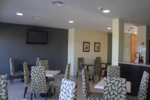 uma sala de jantar com mesas e cadeiras e uma televisão em Hotel Dom Afonso - Monção em Monção