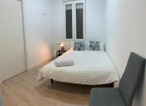 a white bedroom with a bed and a chair at Atocha Reina Sofia in Madrid