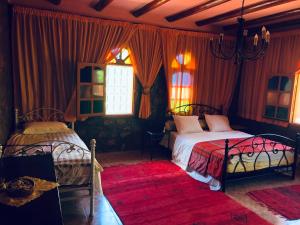 1 dormitorio con 2 camas y cortina roja en Siliya rooms Heart Ameln Valley en Tafraout