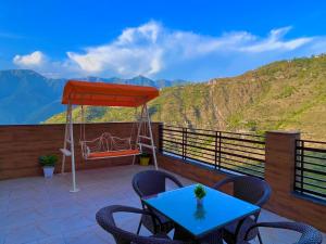 a patio with a blue table and chairs and mountains at Doon Valley Resort, Mussoorie in Mussoorie
