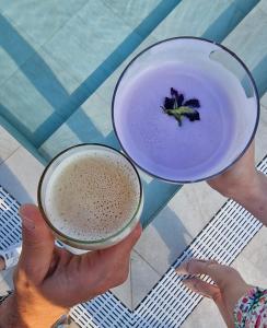 a person holding two cups of coffee and a purple drink at Fantinello Hotel in Caorle