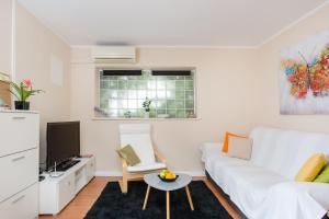 sala de estar blanca con sofá blanco y TV en Dream Apartment Solitudo, en Dubrovnik