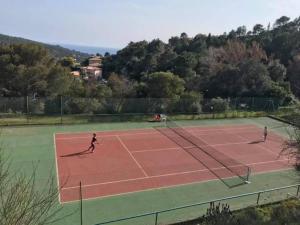 three people playing tennis on a tennis court at Les Issambres Superbe studio avec terrasse in Roquebrune-sur-Argens