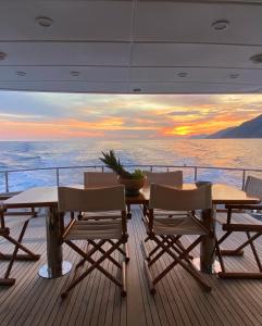 Yacht San Lorenzo 22 في لا سبيتسيا: طاولة وكراسي على سفينة سياحية مع غروب الشمس