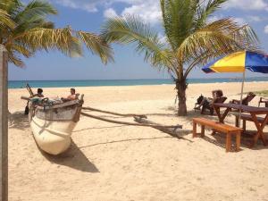a boat on a beach with people sitting on a bench at Aqua Marine Beach Hotel in Kalkudah