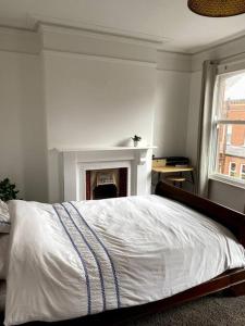 a white bedroom with a bed and a fireplace at The Vintage retreat in Belfast