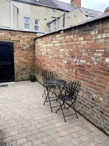 two chairs and a table in front of a brick wall at The Vintage retreat in Belfast