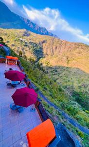 a group of tables with umbrellas on top of a mountain at Doon Nature Valley Resort, Kempty Fall Mussoorie in Mussoorie